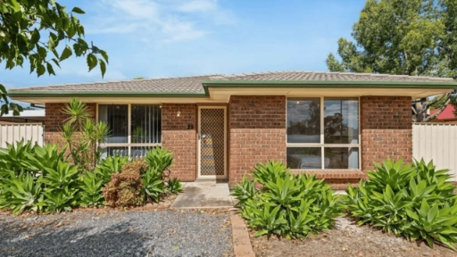 Single-storey brick home with a tiled roof, lawn, and surrounding trees