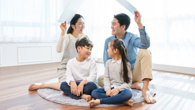 family with two children sitting on the living room floor of a modern new home